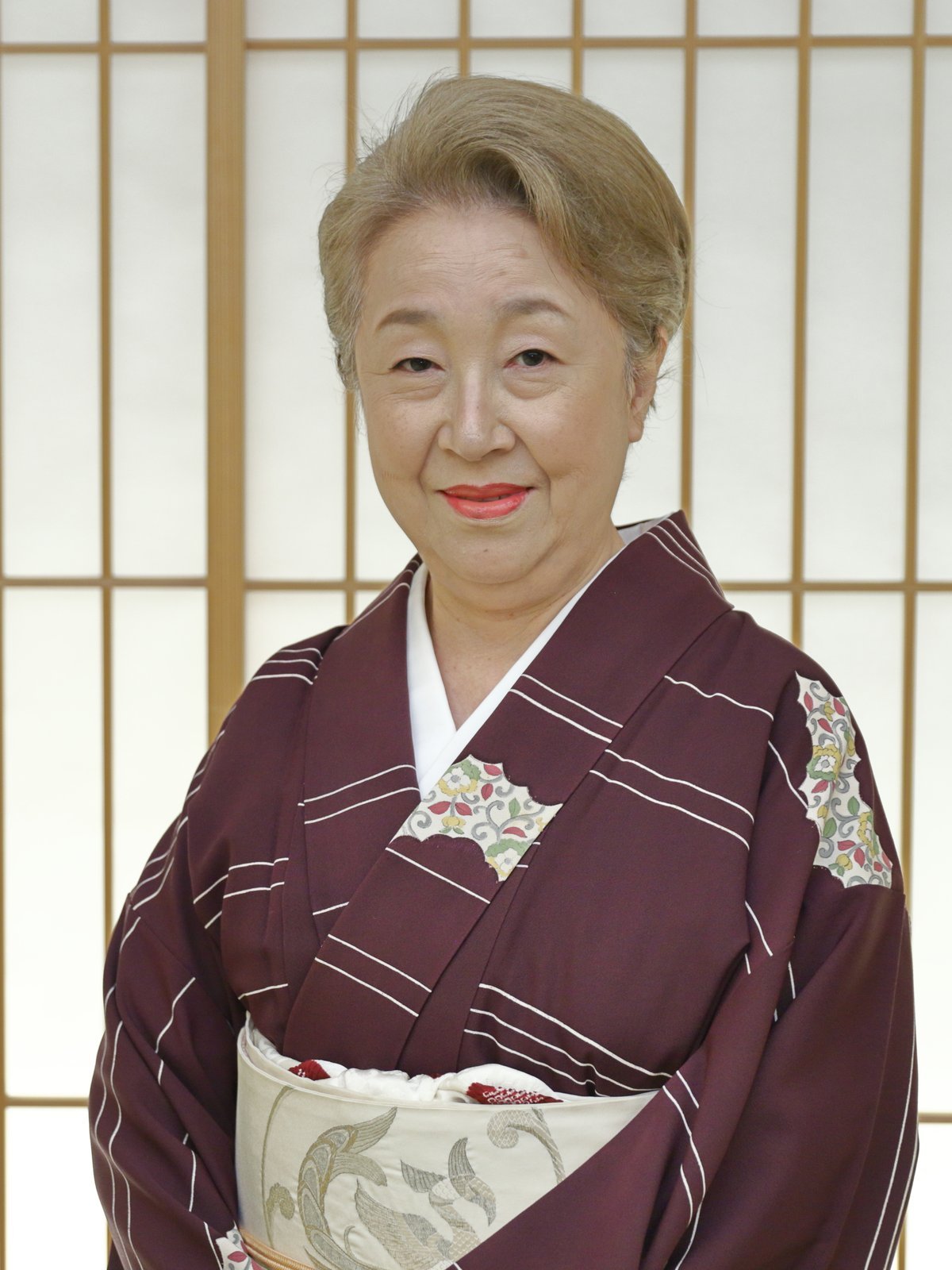 The okami of an Asakusa teahouse, a former geisha, before a shoji screen