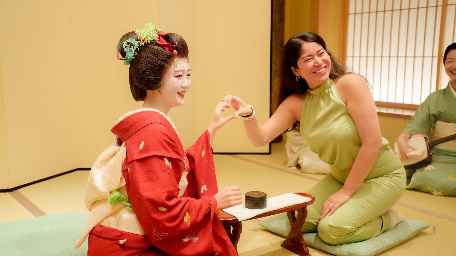 An Asakusa hangyoku in a red furisode playing a banquet game with a guest, a jikata beside her