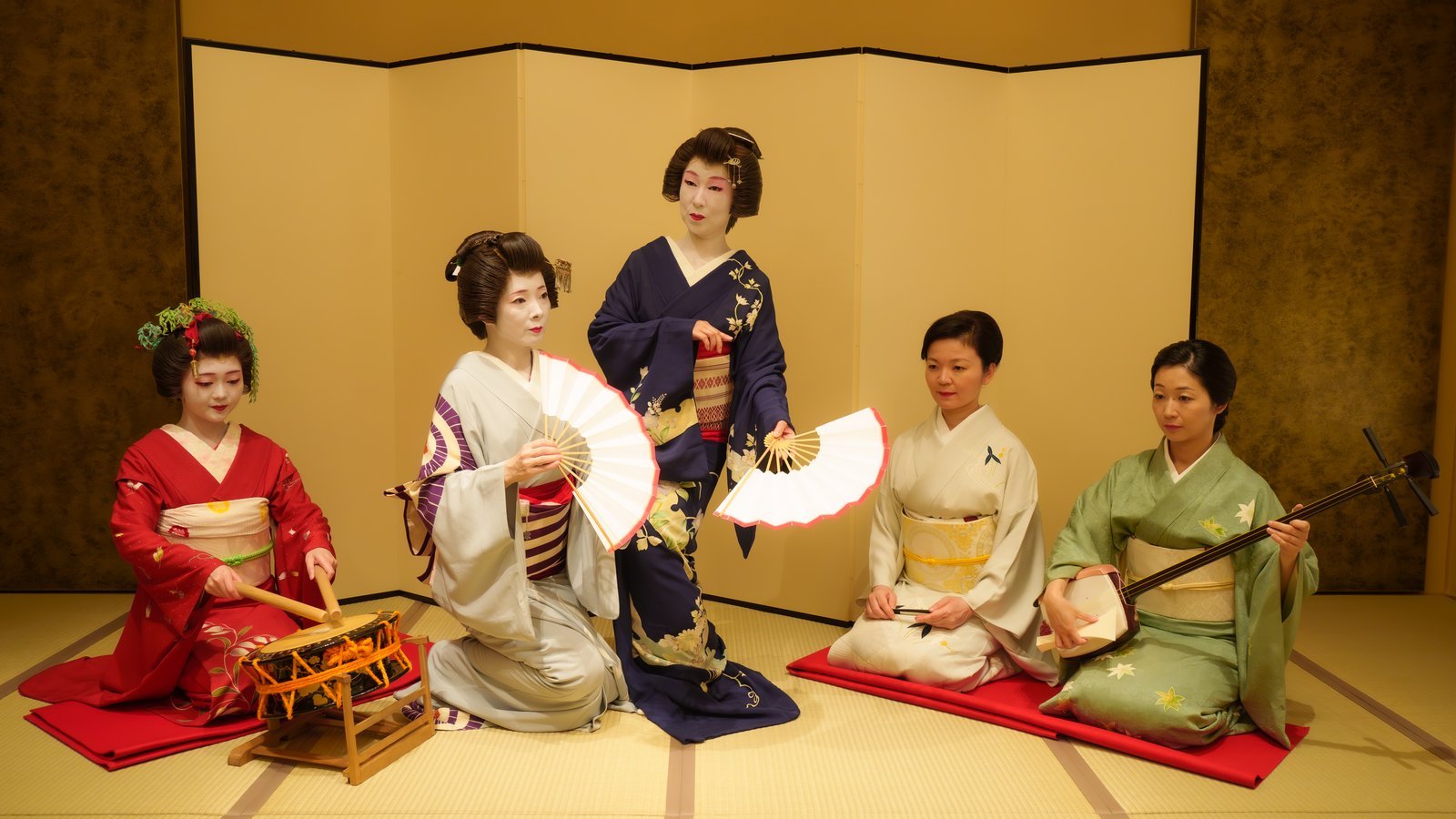 Tachikata dancers in white makeup and nihongami beside jikata musicians without white makeup at an Asakusa ozashiki