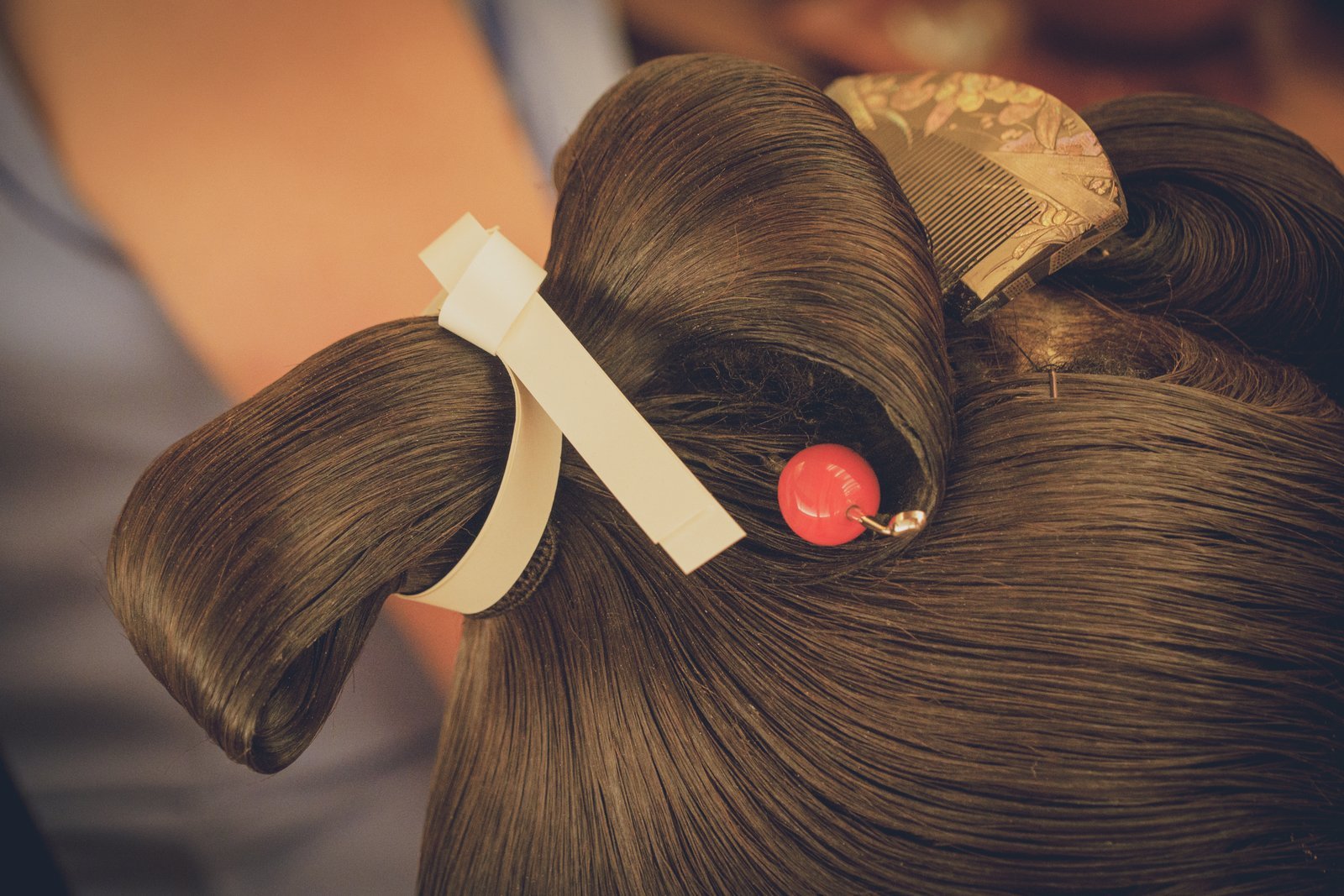 The back of a geisha's nihongami with a decorated comb and kanzashi hairpin set into the knot