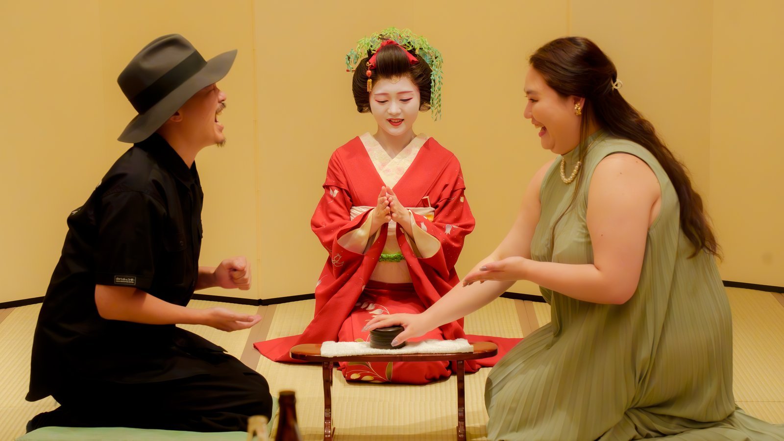 A hangyoku, an apprentice geisha in Asakusa, in a red furisode, acting as referee while two guests play a banquet game