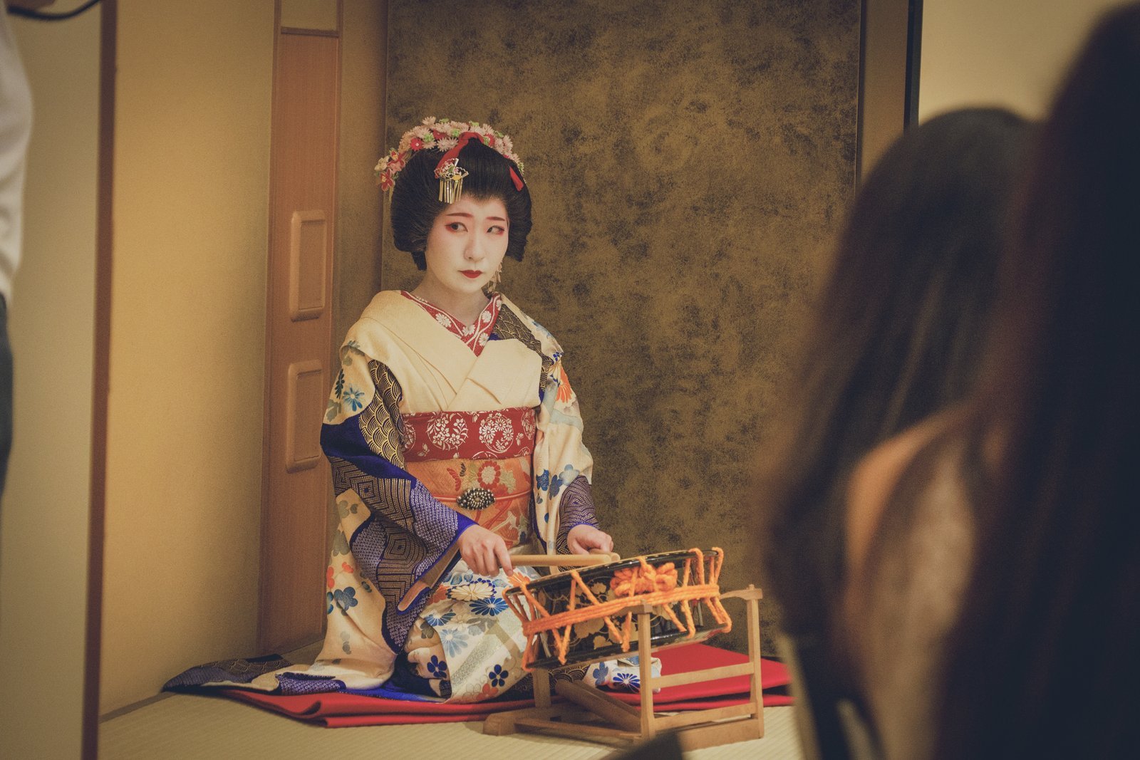 A young Asakusa geisha playing the drum at an ozashiki