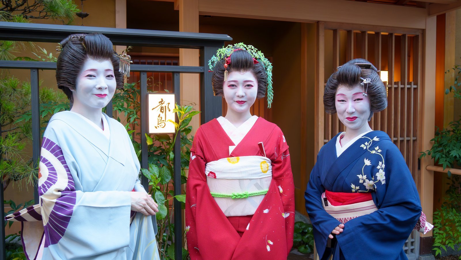 An Asakusa hangyoku in a red kimono between two geisha, dressed in the Tokyo style of understated iki