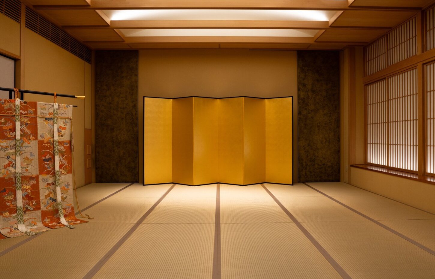 The main tatami room of an Asakusa house that hosts geisha evenings, with a gold folding screen set at the far end