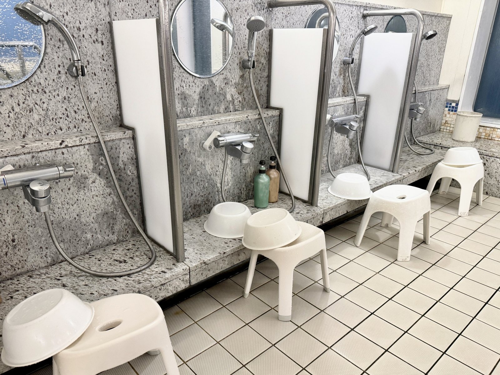 A clean, modern washing area in a Japanese bathhouse with showers and stools