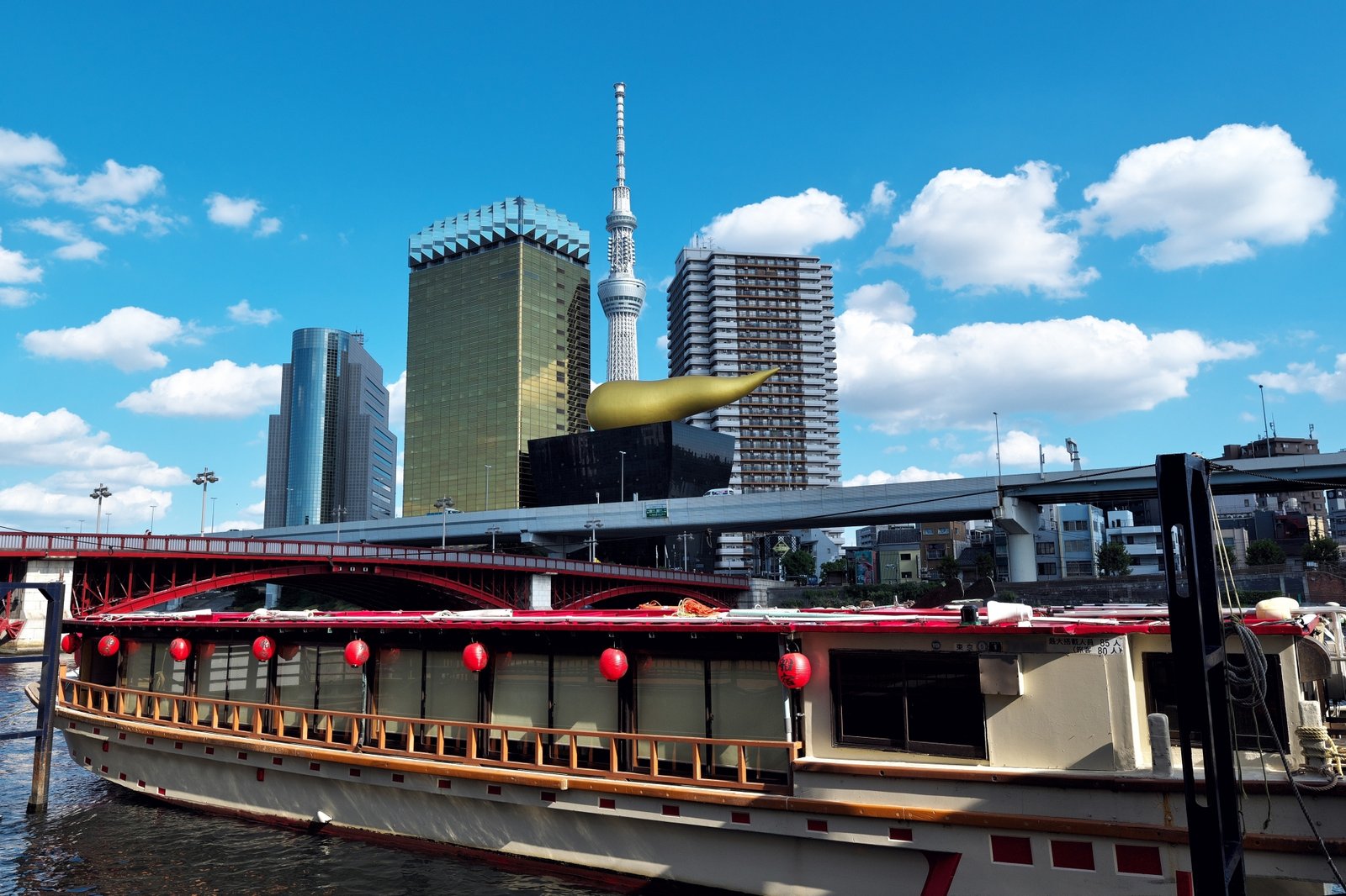 A yakatabune boat on the Sumida River with Tokyo Skytree behind it