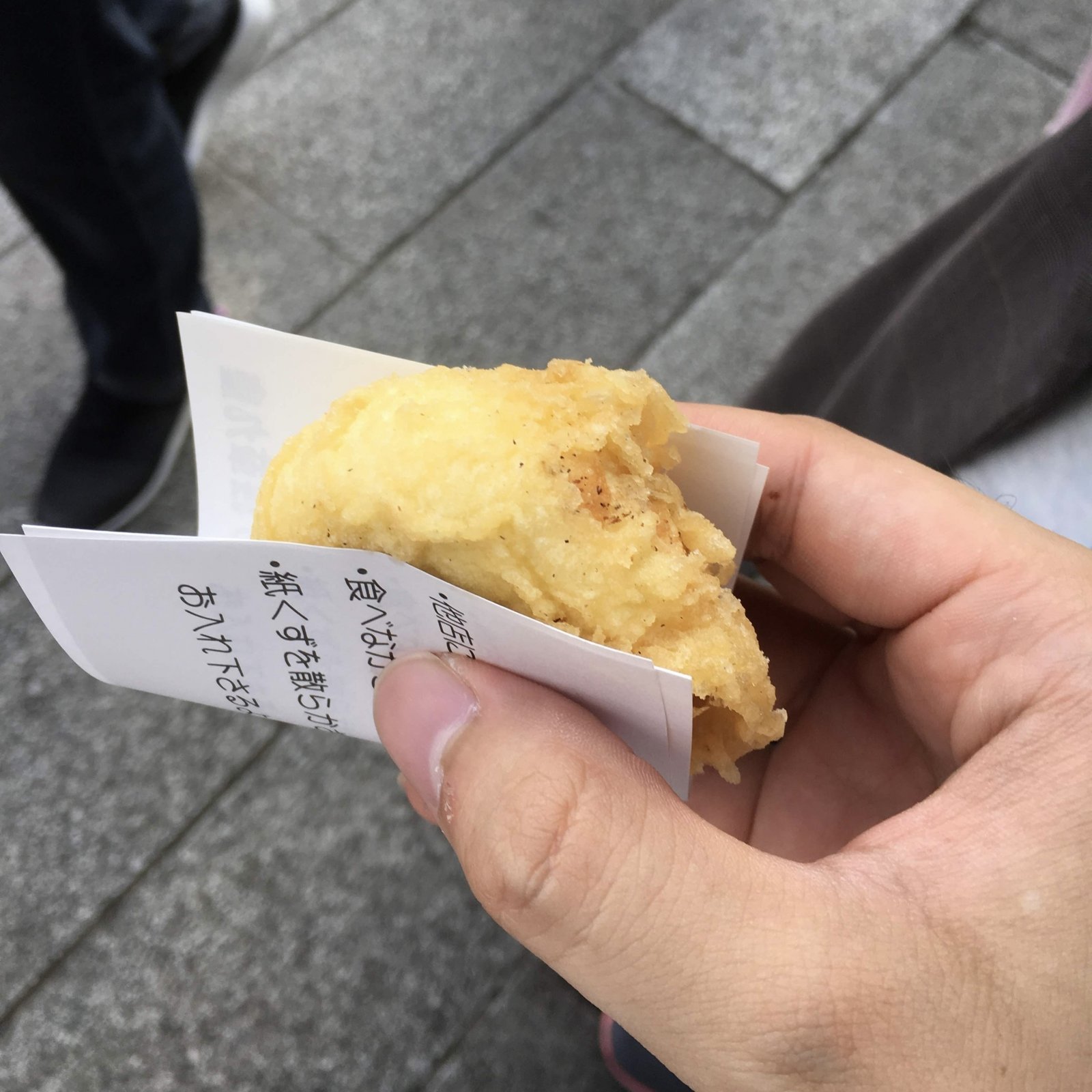 Holding a freshly fried agemanju bun wrapped in paper