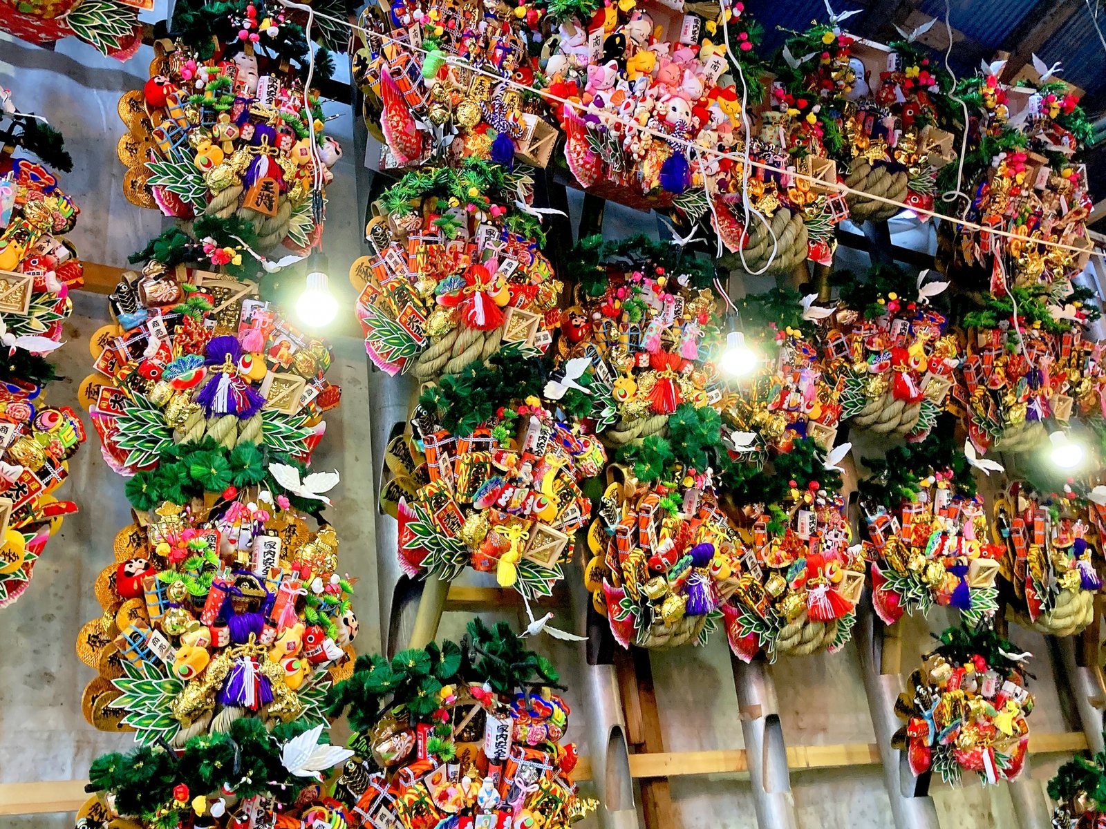Rows of kumade rakes hanging under lights at a Tori no Ichi stall in Asakusa