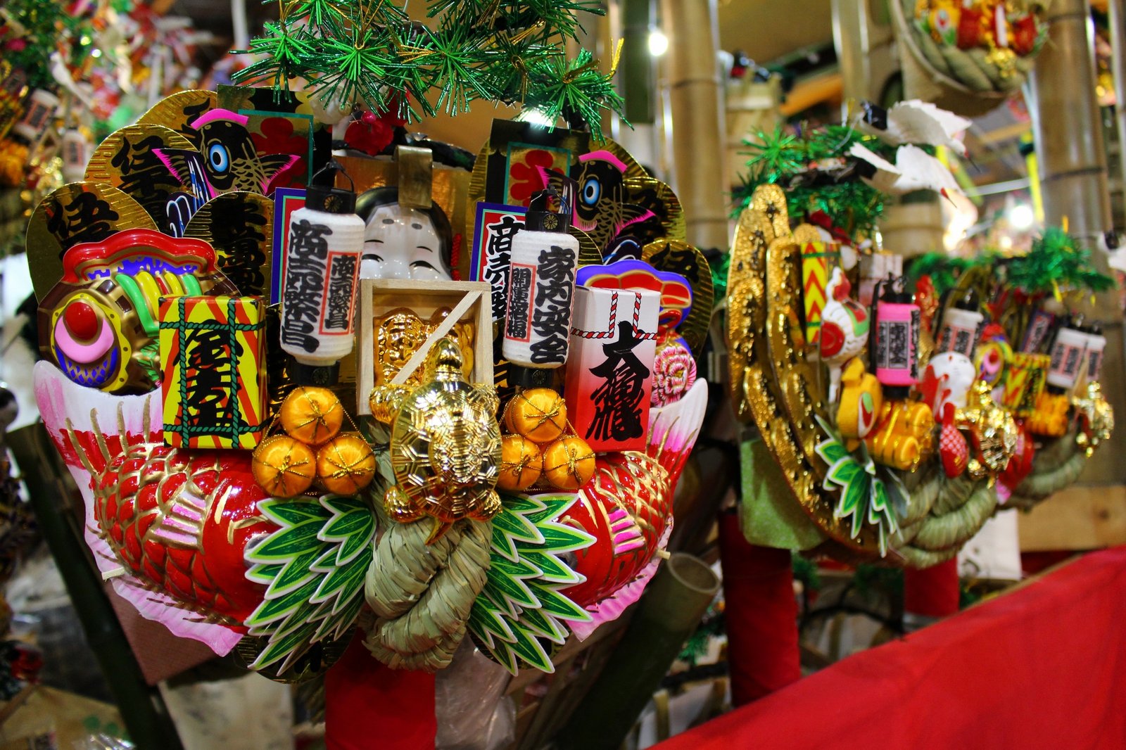 Close-up of a lucky kumade decorated with an Okame mask, sea bream, and gold coins
